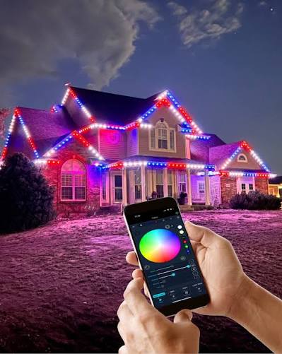 Hand holding a phone with a color-picker app, house lit red white and blue in the background