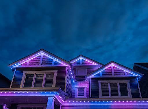Modern two-story home with pink and purple permanent roofline lighting