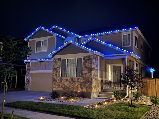 Stone home with blue permanent roofline lighting