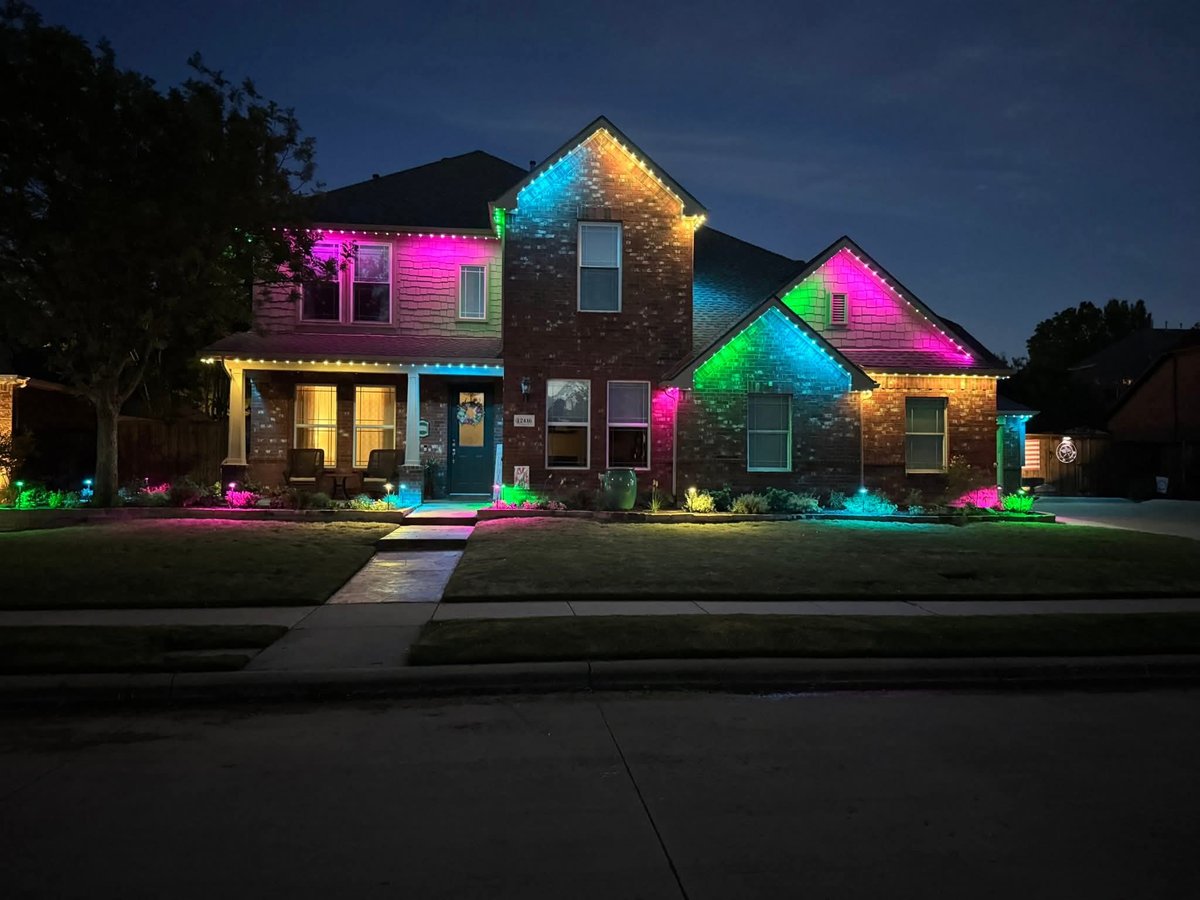 Brick home with colorful pink, green and blue permanent uplighting and roofline lighting