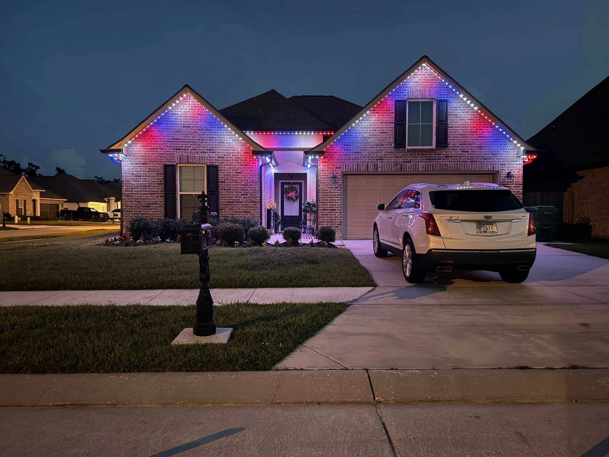 Brick home with red, white and blue permanent roofline lighting