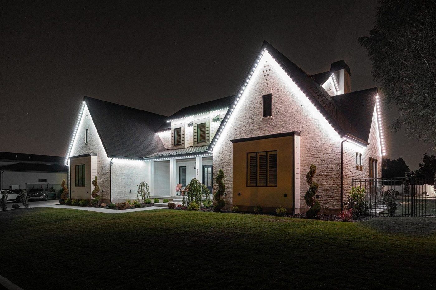 White brick modern farmhouse with cool white permanent roofline lighting