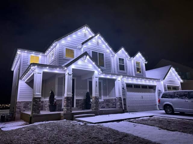 Home with cool white permanent roofline lighting in the snow