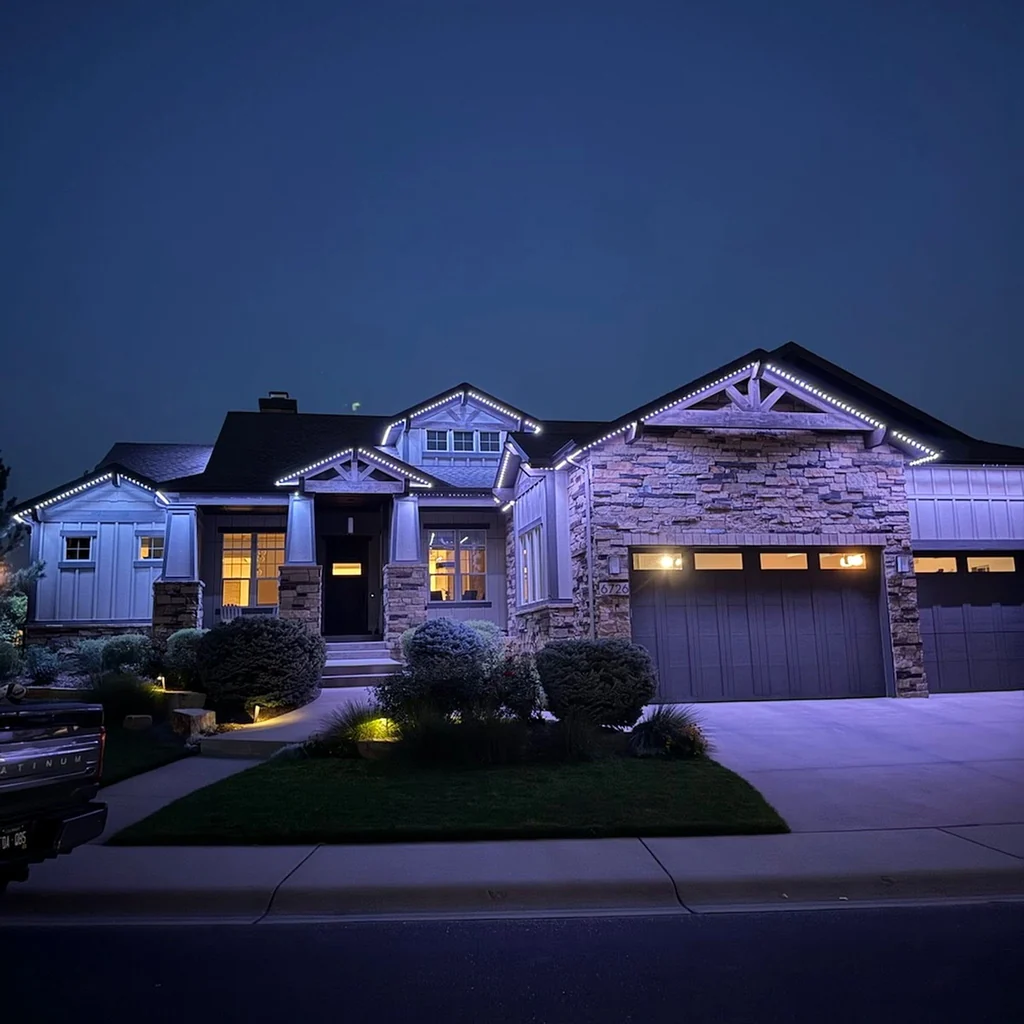 Stone craftsman home with cool white permanent lighting